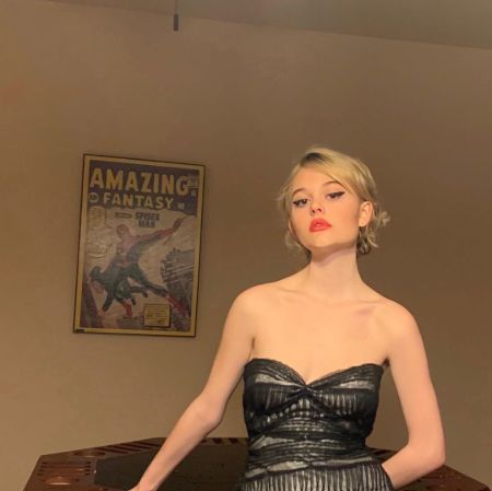 Emily Alyn Lind in a black dress poses for a picture.
